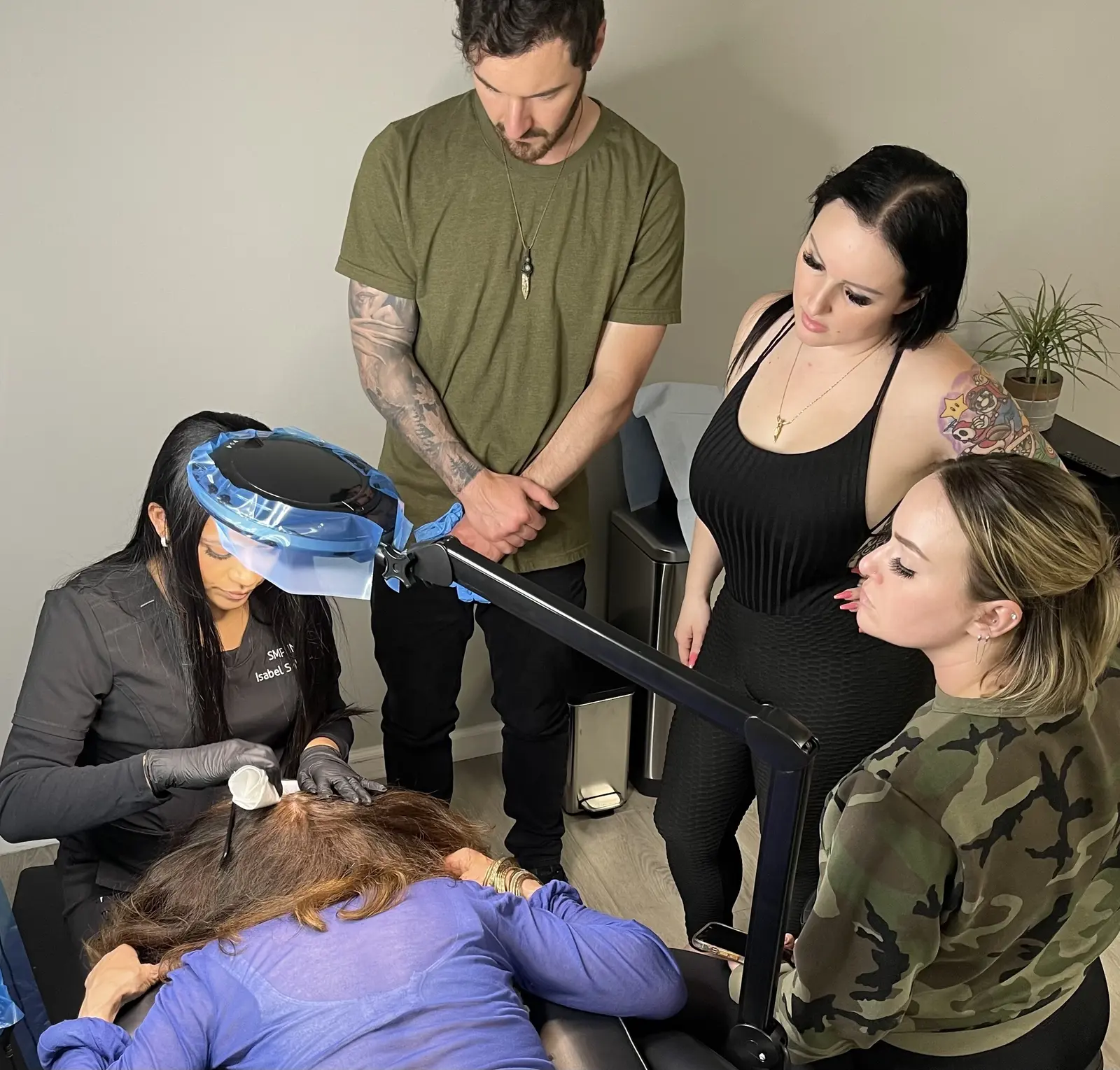 Trainees observing a live scalp micropigmentation demonstration on a model